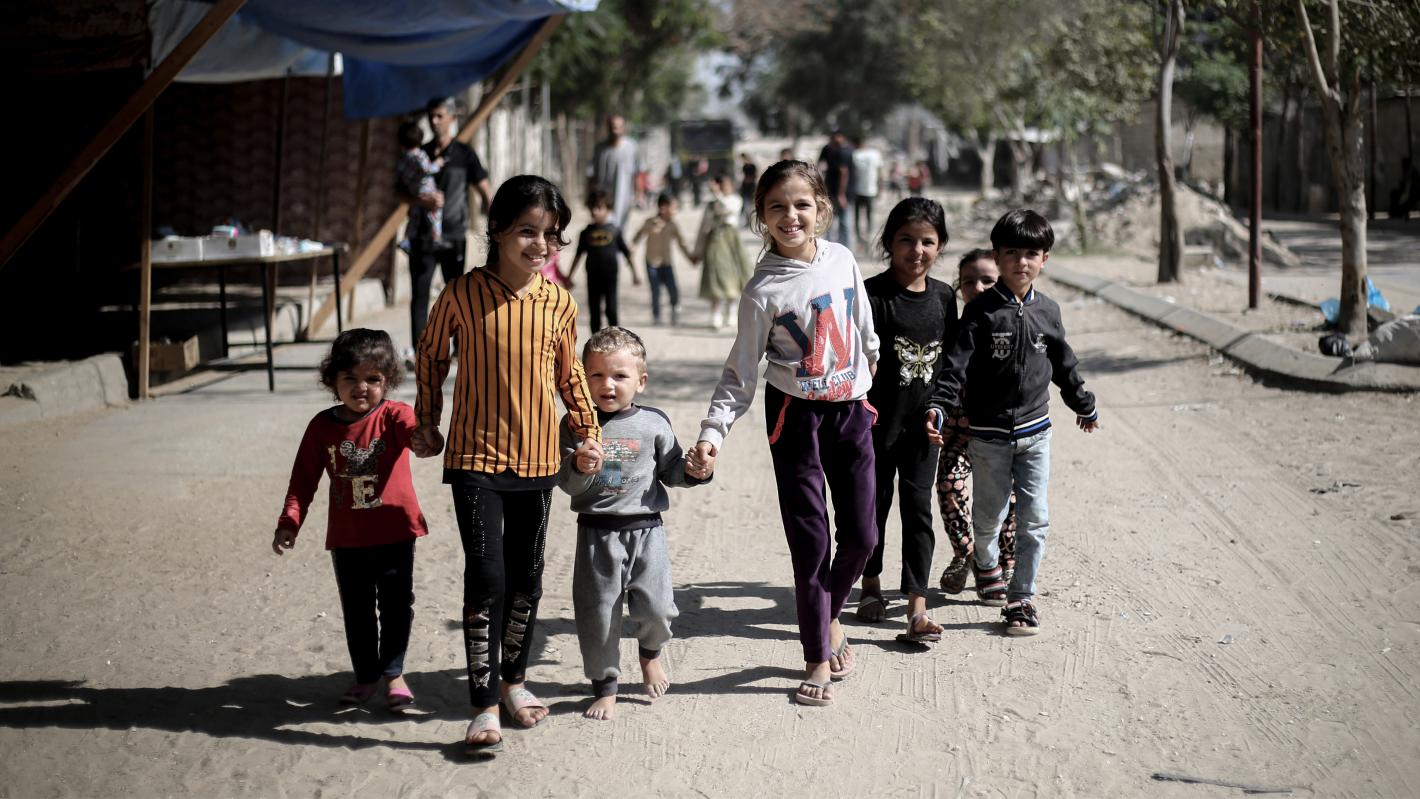 A group of children holding hand in a camp in Gaza.