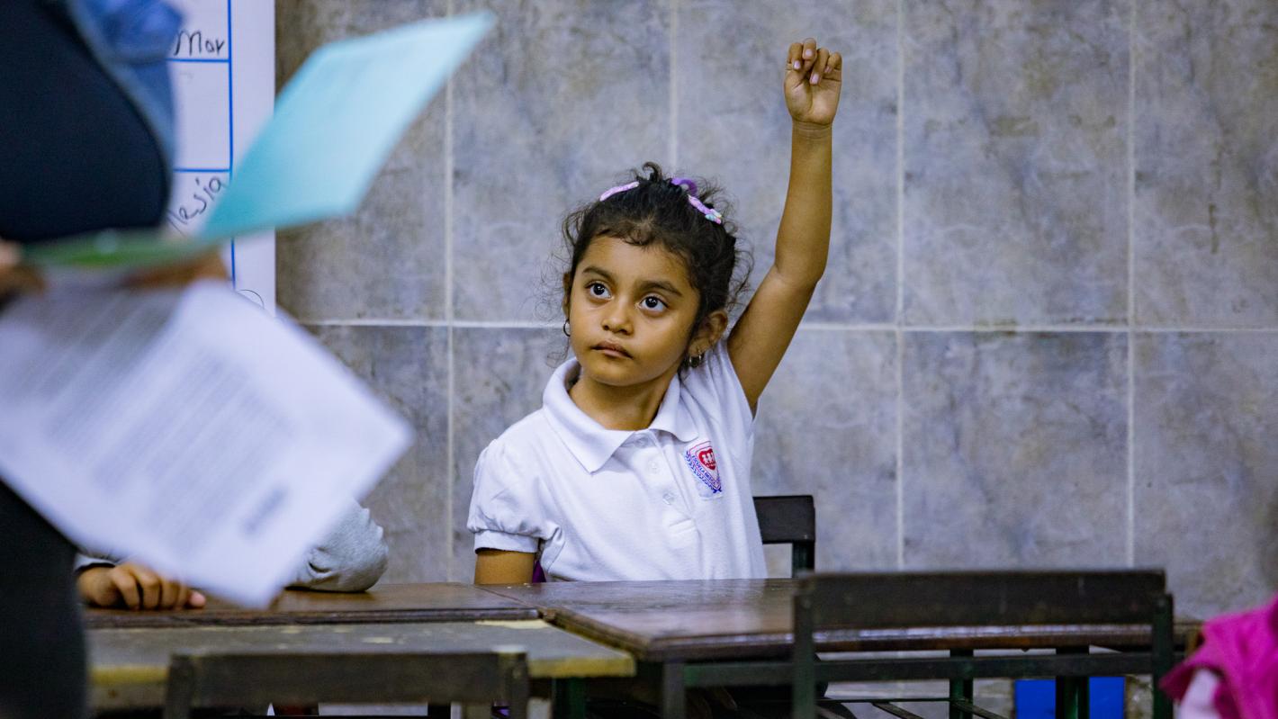 Child from Venezuela raising hand to ask a question