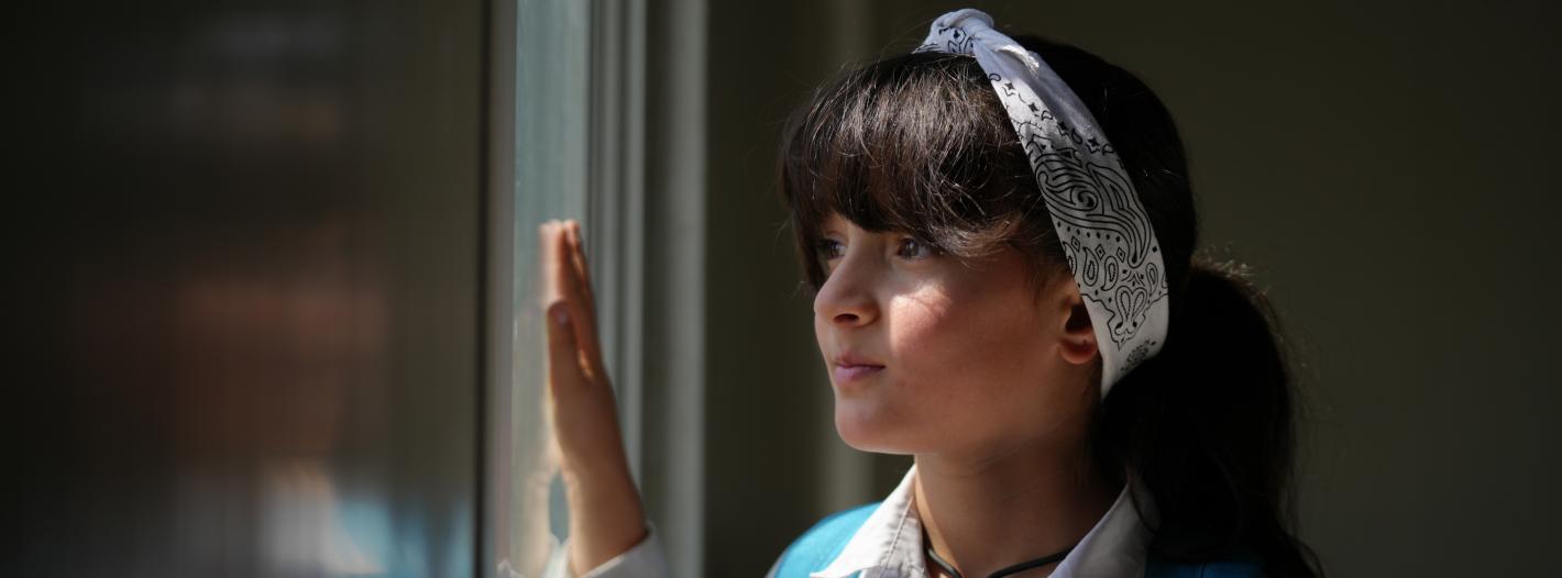 A girl looking out of a glass window.